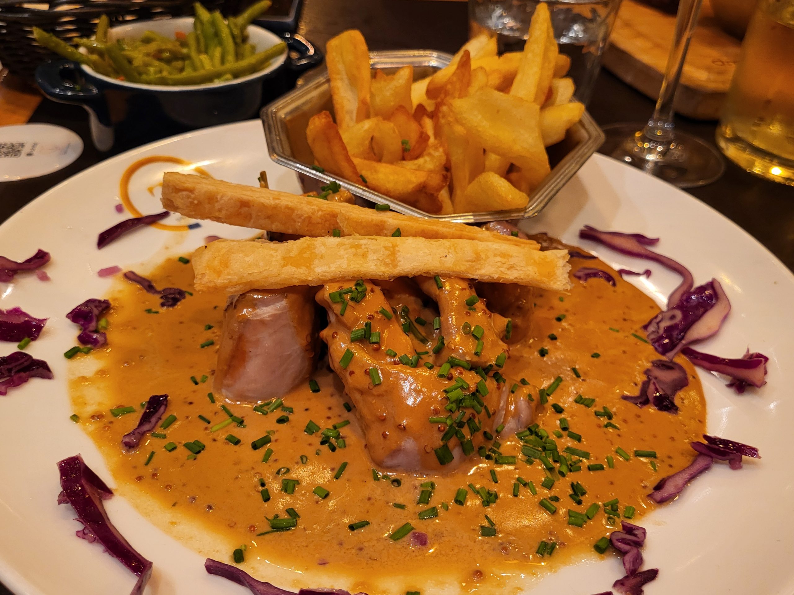 Rabbit in a creamy mustard sauce with chips and green beans on the side, a classic bistro main course
