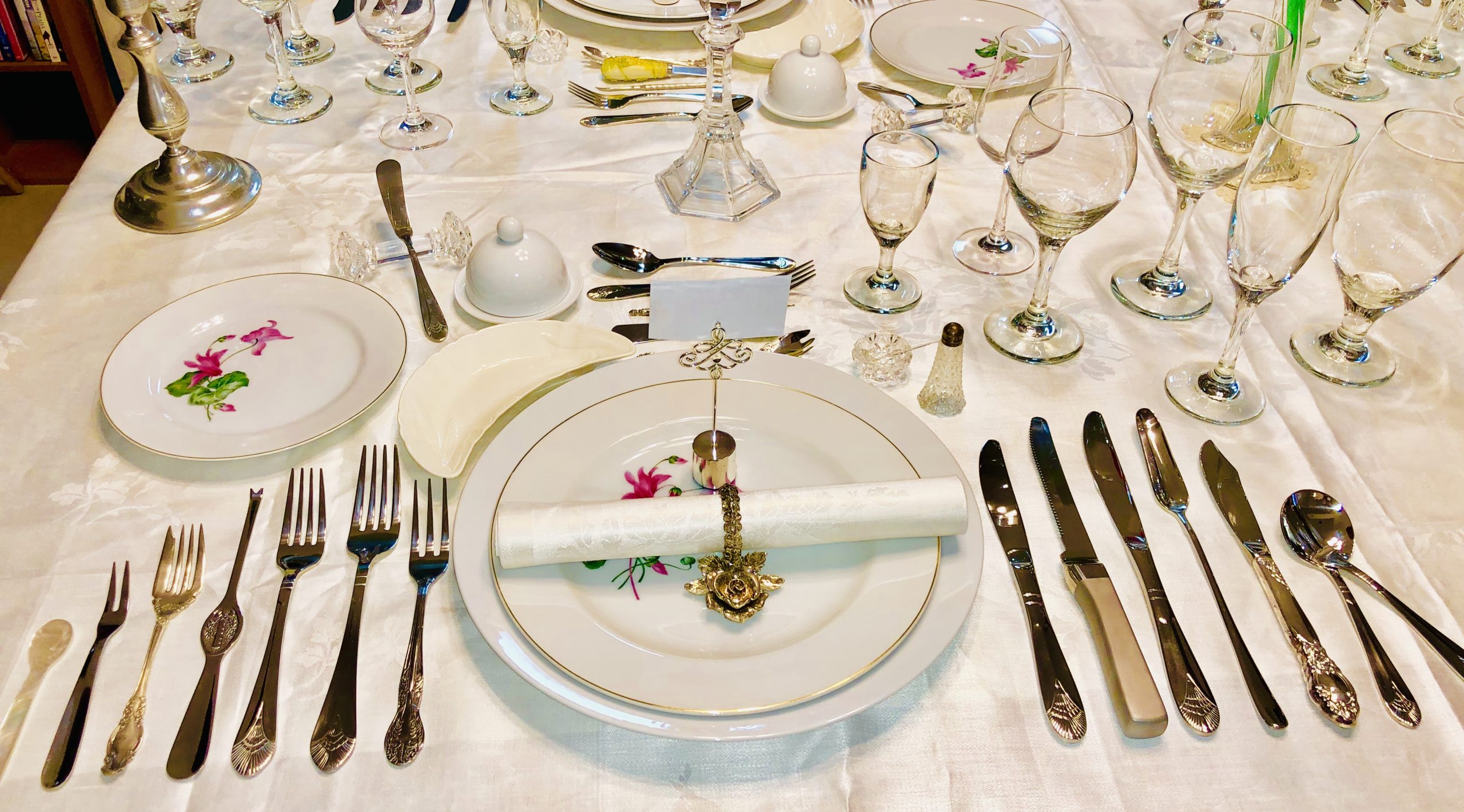 A formal place setting with rows of forks to the left, knives and spoons to the right, and glasses above
