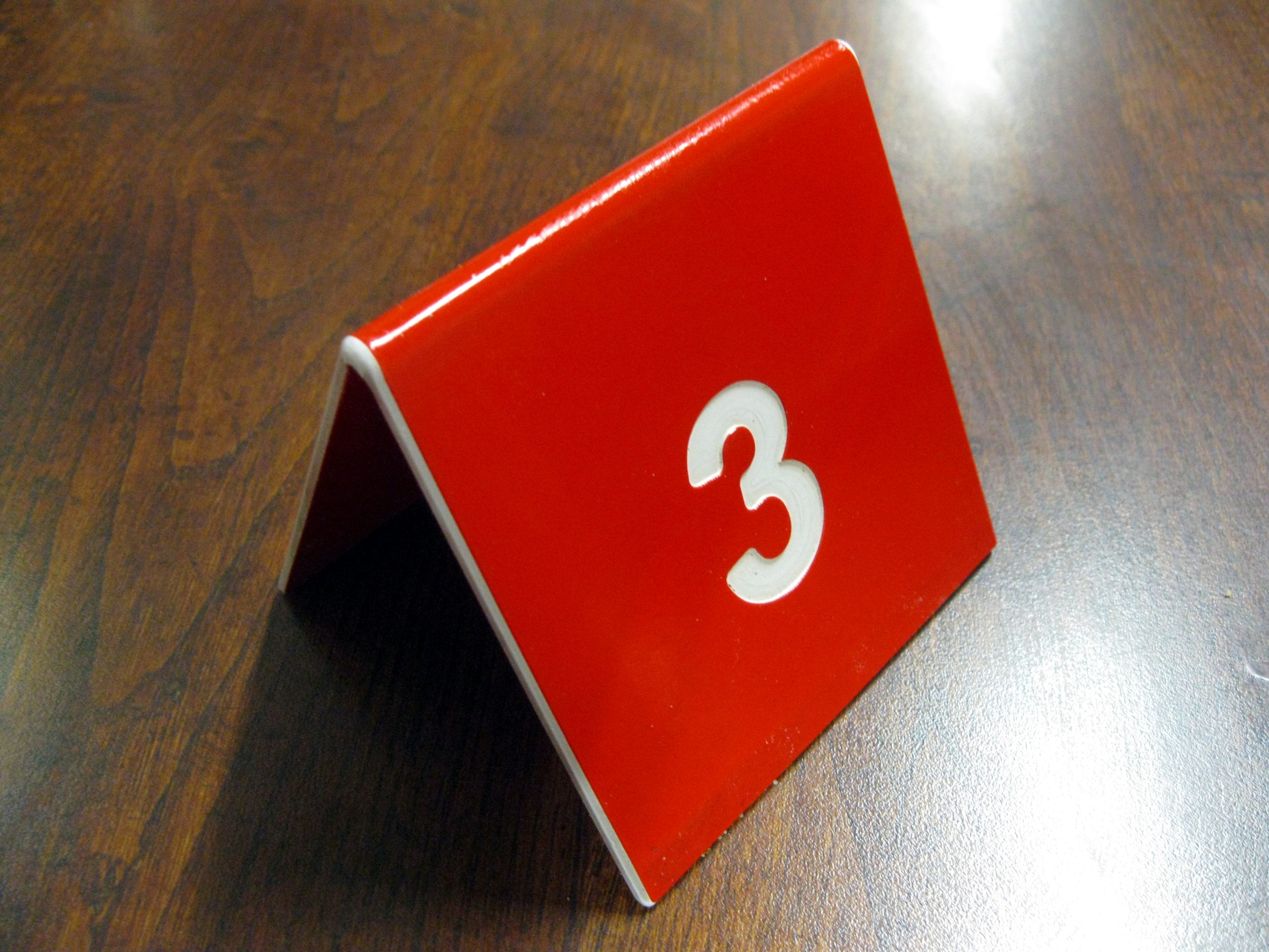 A red table number marker standing on a wooden table, used so staff can bring an order to the right seat