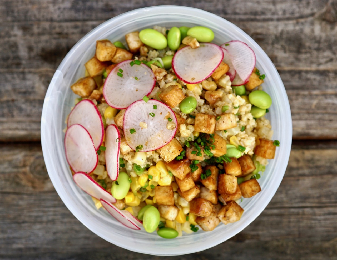 A made-to-order grain bowl of millet, crispy tofu, edamame, sweetcorn and sliced radish