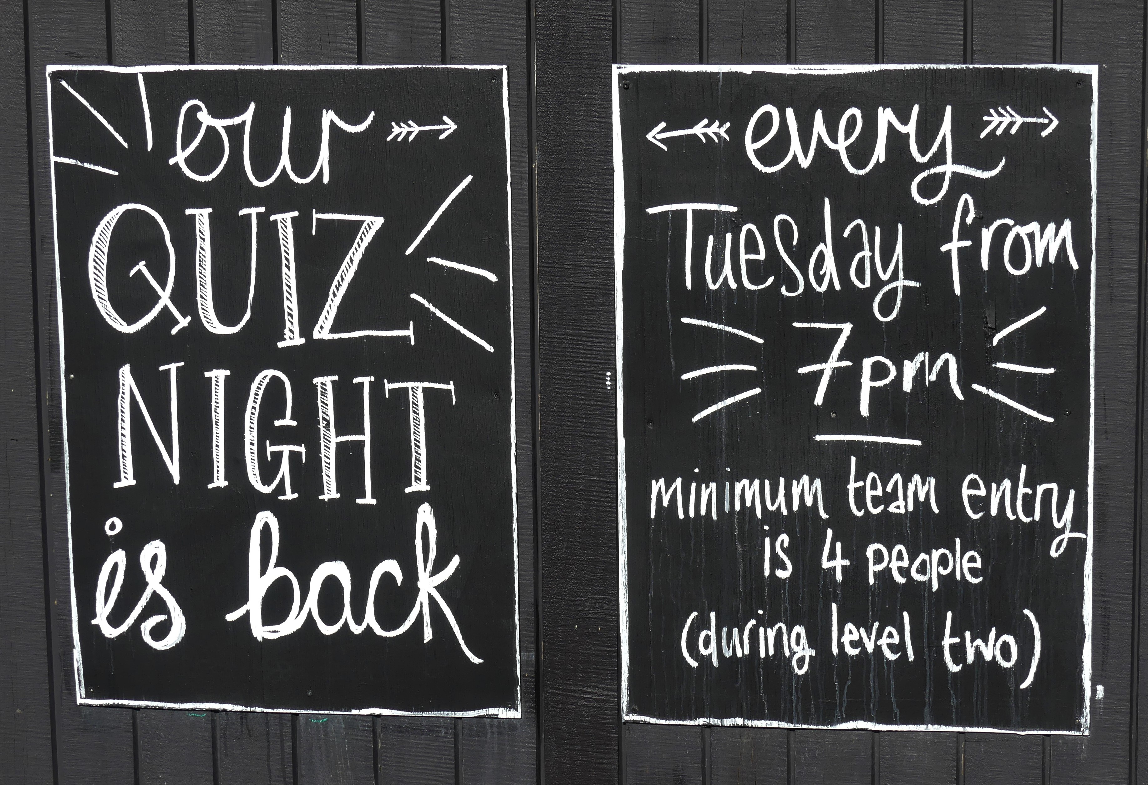 Hand-lettered chalkboard announcing a weekly quiz night every Tuesday from 7pm
