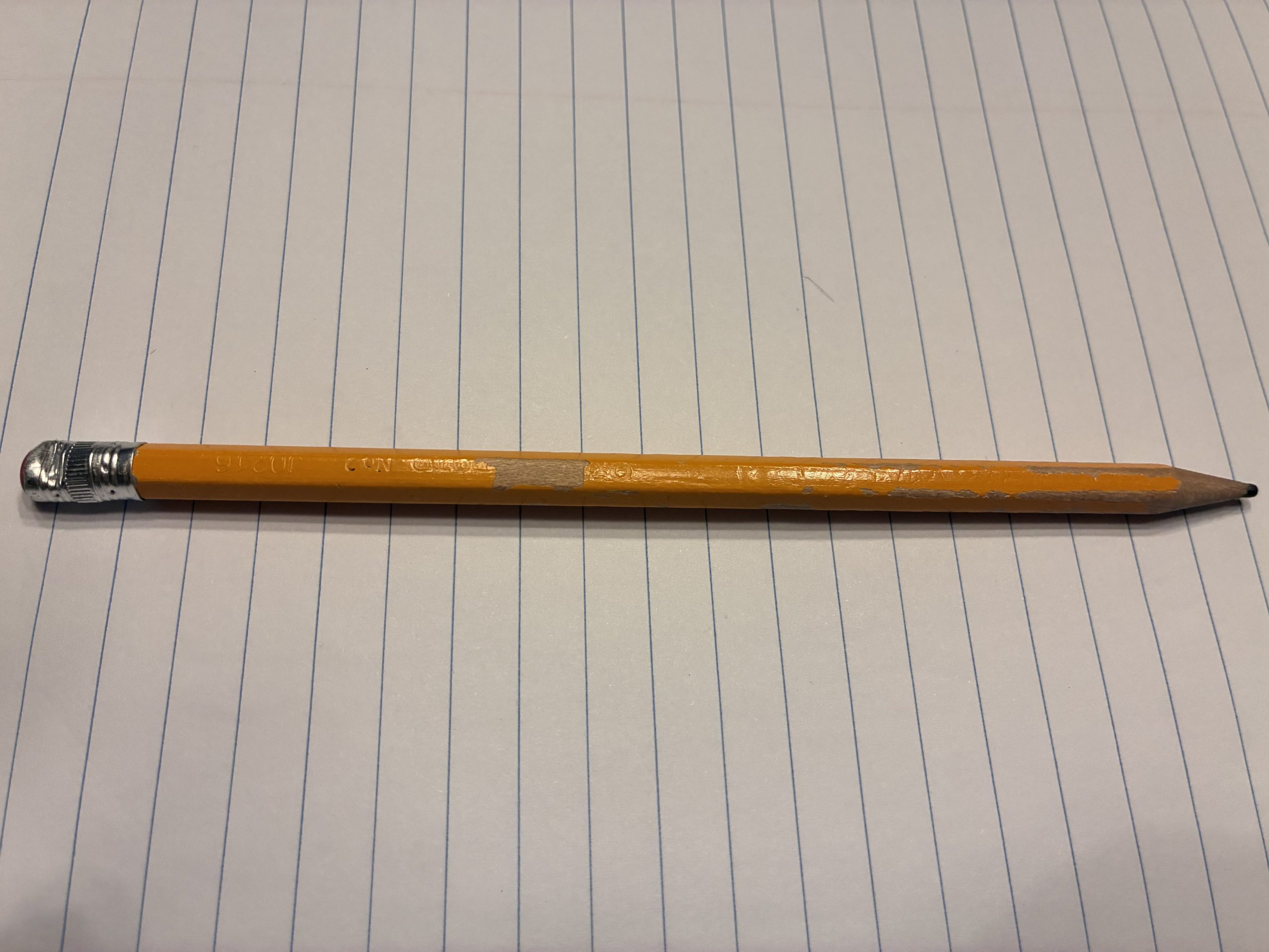 A well-used pencil lying on lined paper, ready for writing down quiz answers