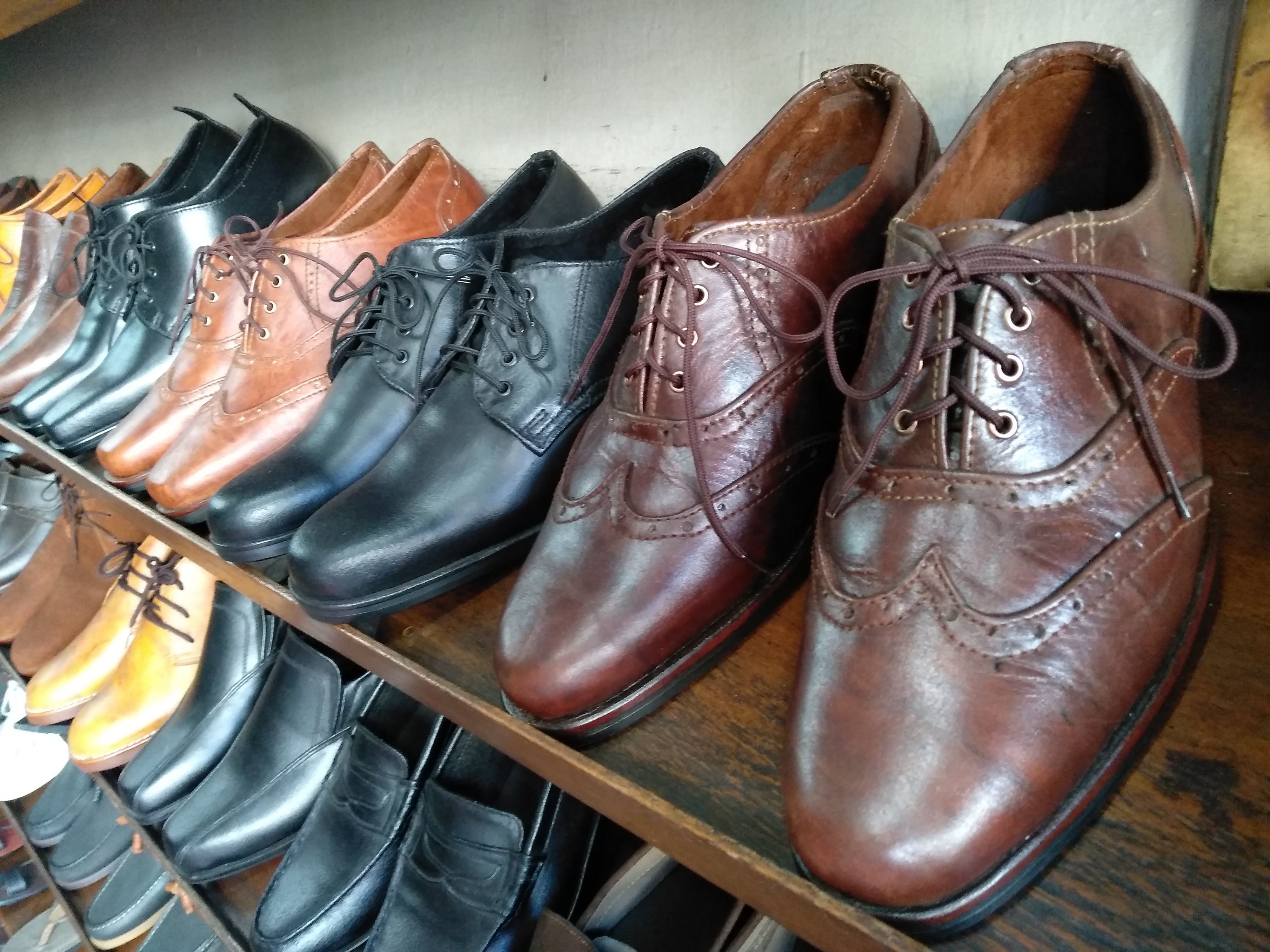 Rows of polished leather lace-up shoes in brown and black on a wooden shelf
